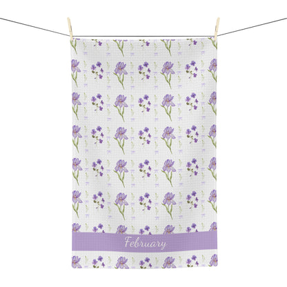 White microfiber tea towel with purple irises, violets, and "February" text, hanging on a line.