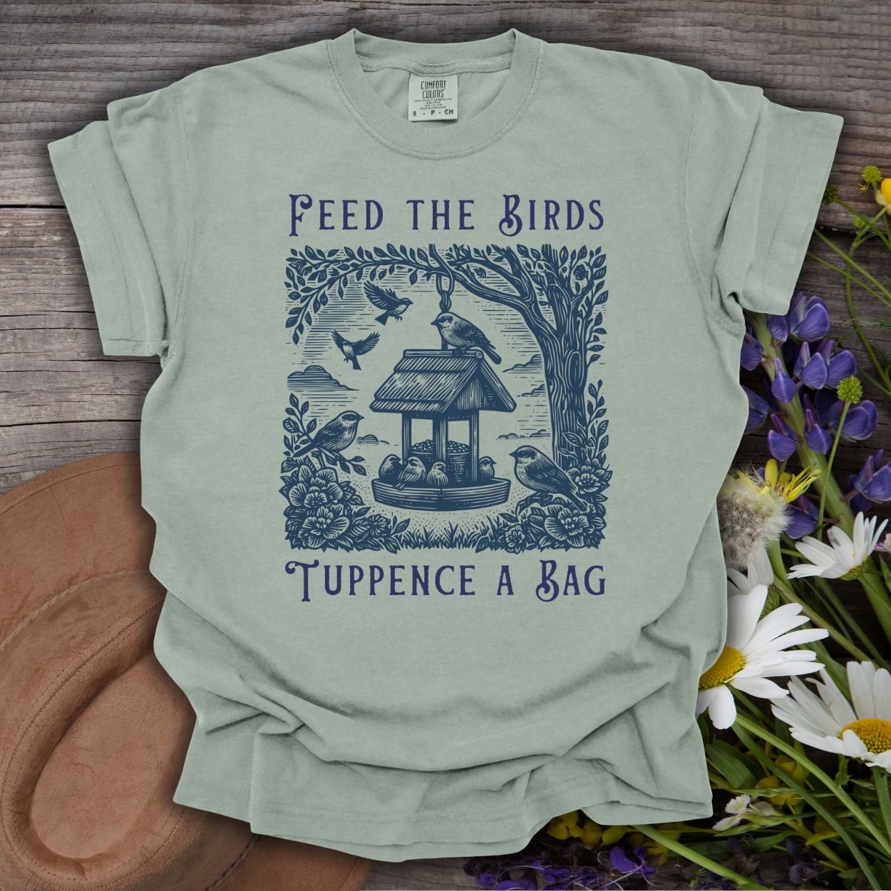 Bay green unisex t-shirt with vintage-style illustration of a bird feeder, finches, sparrows, and "Feed the Birds Tuppence a Bag" text.