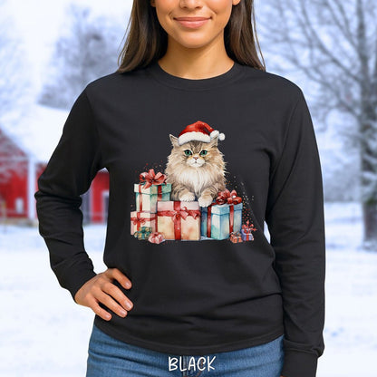A woman wearing a black long-sleeve t-shirt with a graphic of a fluffy cat wearing a Santa hat and sitting on wrapped Christmas presents. The background is a blurred snowy outdoor scene.