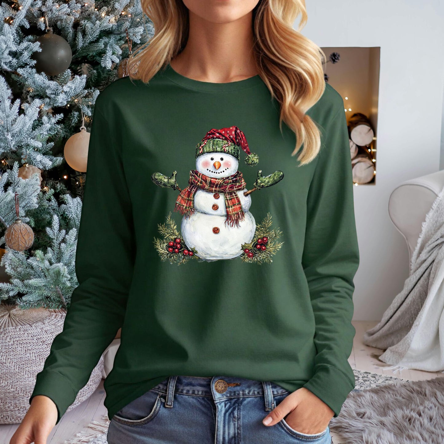 Green long-sleeve tee with a watercolor snowman wearing a plaid hat, green gloves, and scarf, surrounded by holly.