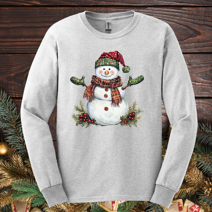 Ash long sleeve tee with a watercolor snowman in a plaid hat, scarf, and green gloves.