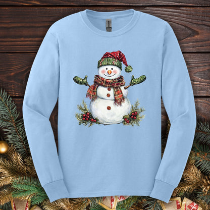 Light blue long sleeve tee with watercolor snowman, plaid hat/scarf, green gloves, holly.