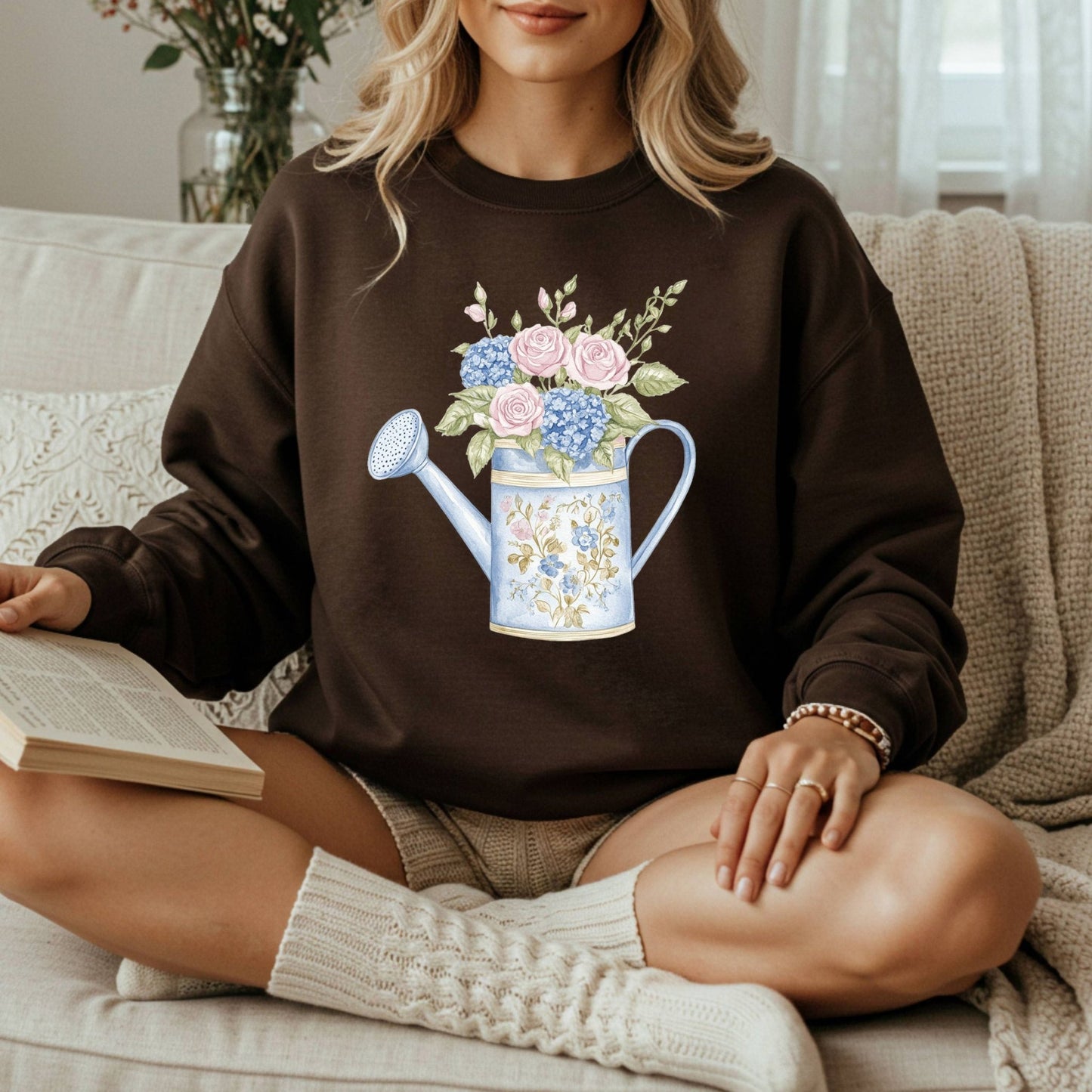 Brown crewneck sweatshirt with a watercolor watering can full of pastel roses and hydrangeas.