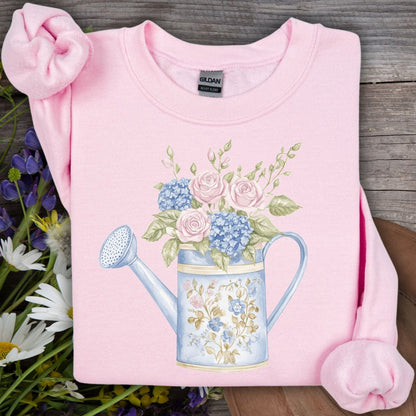 Light pink crewneck sweatshirt with a watercolor floral watering can design.