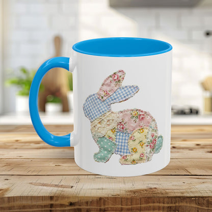 White ceramic mug with blue handle and interior, featuring a patchwork floral Easter bunny design.