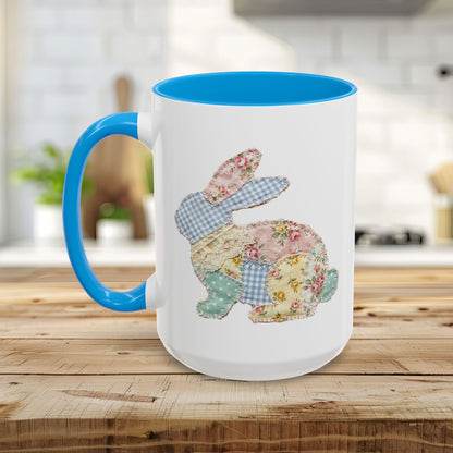 White ceramic mug with blue handle and interior, featuring a patchwork floral Easter bunny design.