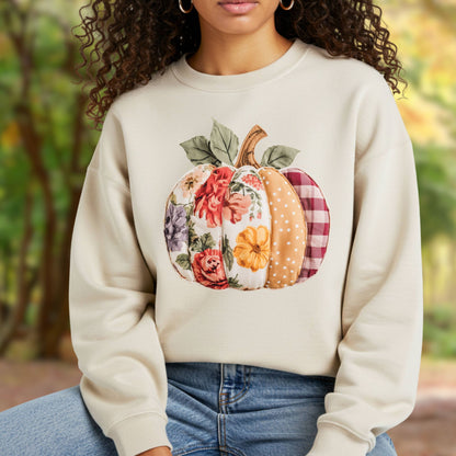 Heathered beige crewneck sweatshirt with a faux patchwork pumpkin design featuring floral, gingham, and polka dot patterns.