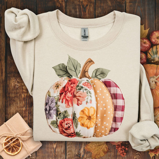 Sand crewneck sweatshirt with a faux patchwork pumpkin design featuring floral, gingham, and polka dot patterns.