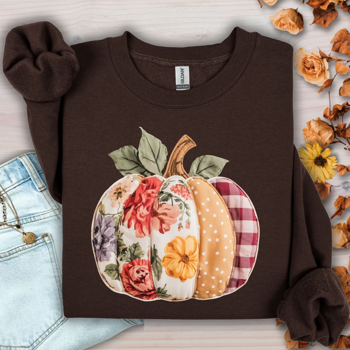 Dark chocolate crewneck sweatshirt with a faux patchwork pumpkin design featuring floral, gingham, and polka dot patterns.