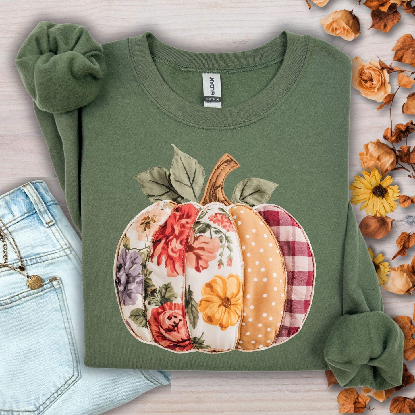 Military green sweatshirt with a faux patchwork pumpkin design featuring floral, gingham, and polka dot patterns.
