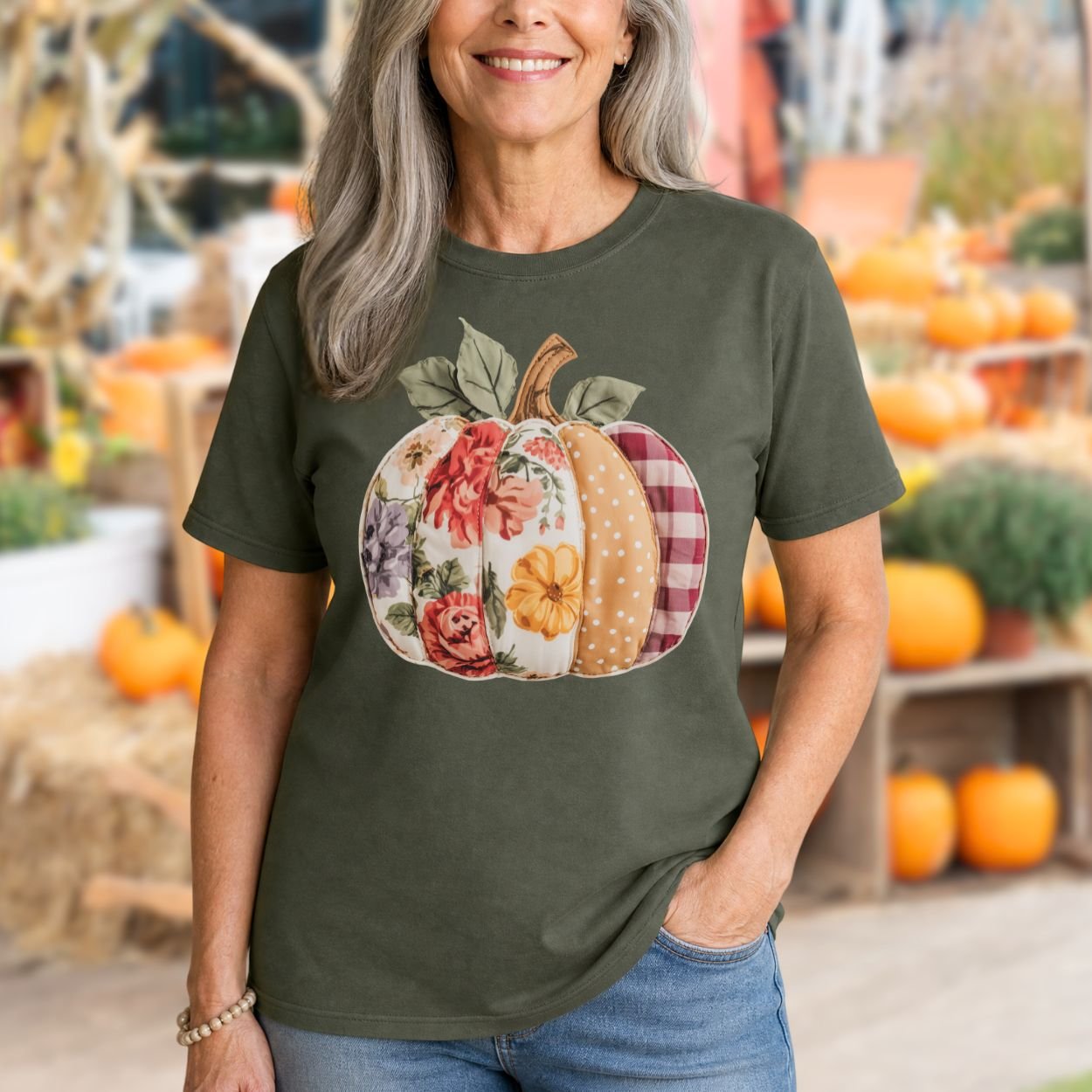 Woman in a Comfort Colors olive green t-shirt with a floral and plaid patchwork pumpkin design.