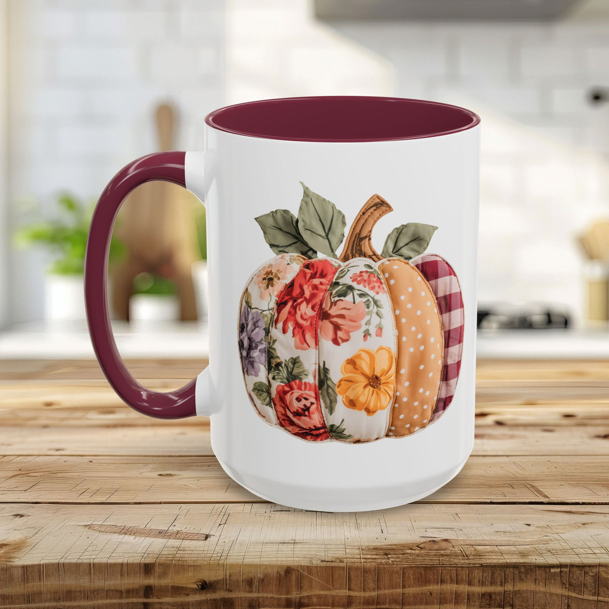 White ceramic mug with burgundy handle and interior, featuring a colorful patchwork floral and plaid pumpkin design.