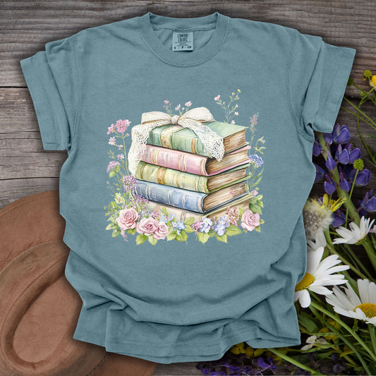 Ice Blue S t-shirt with a watercolor stack of vintage books, lace ribbon, roses, and wildflowers.