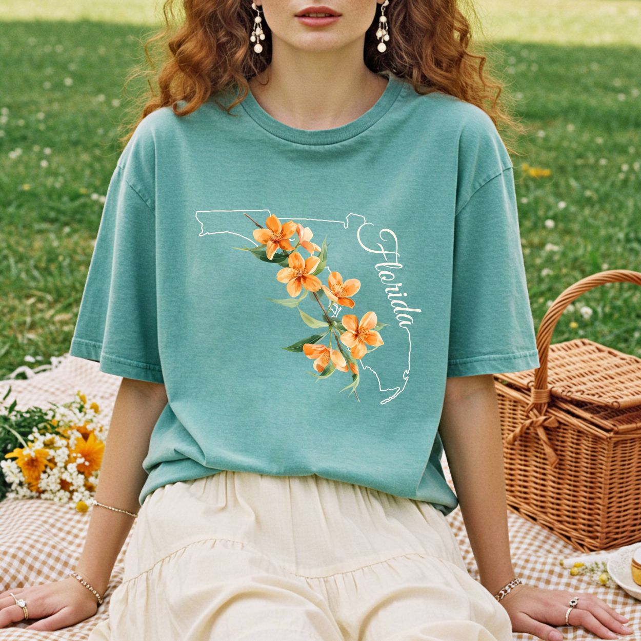 Relaxed-fit, garment-dyed teal t-shirt with a white Florida outline and orange blossom design.