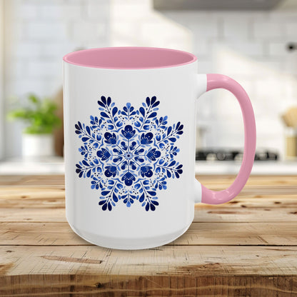 White ceramic mug with a pink interior and handle, featuring a blue floral snowflake design.