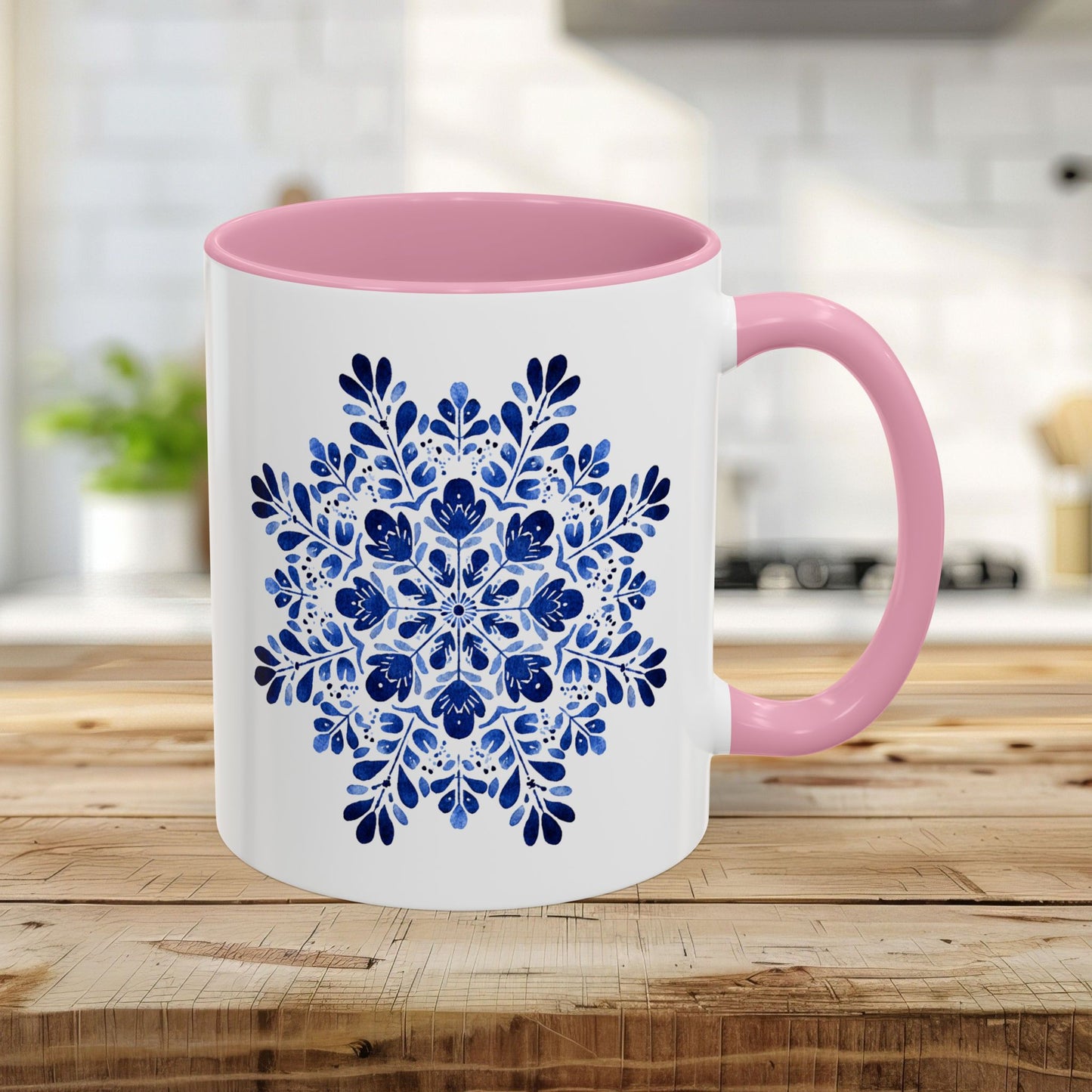 11oz white ceramic mug with a pink interior/handle and a blue floral snowflake mandala design.