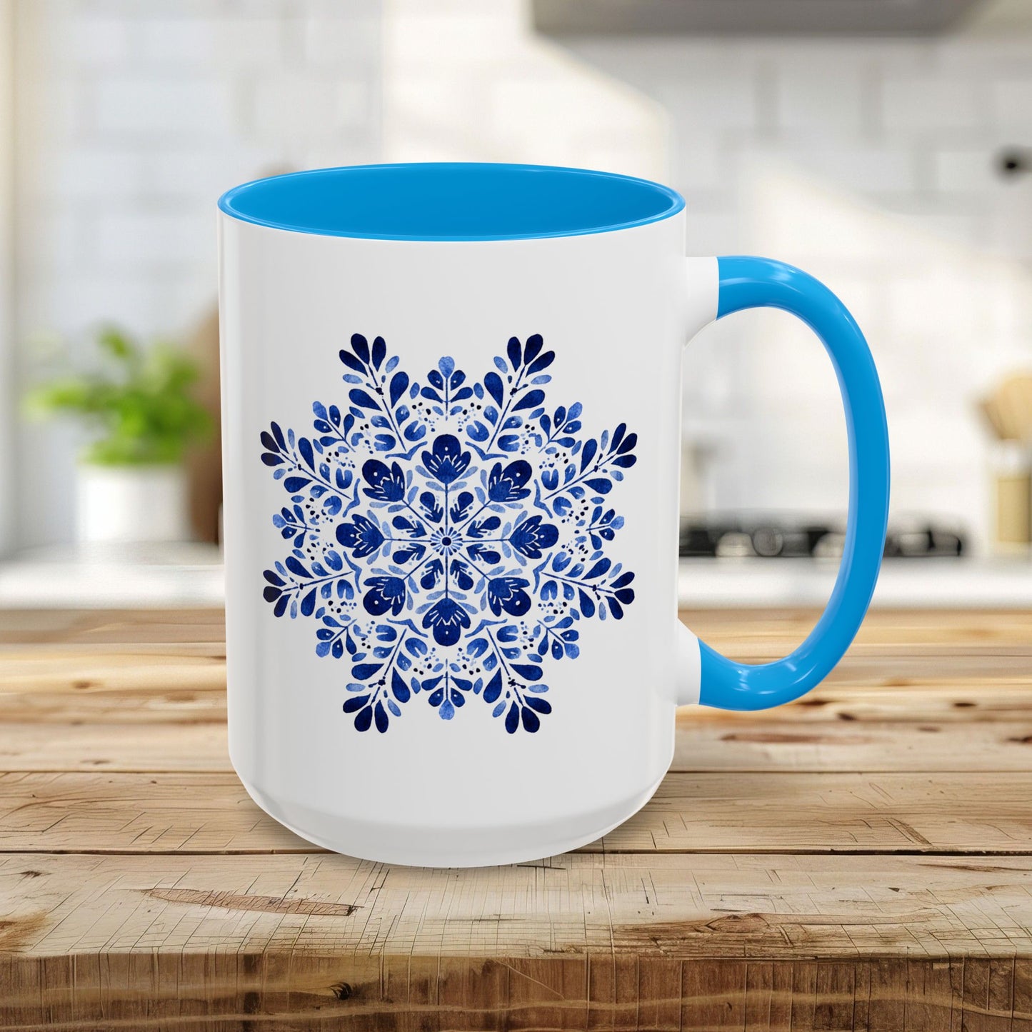 15oz white ceramic mug with light blue interior and handle, featuring a detailed blue floral snowflake mandala.