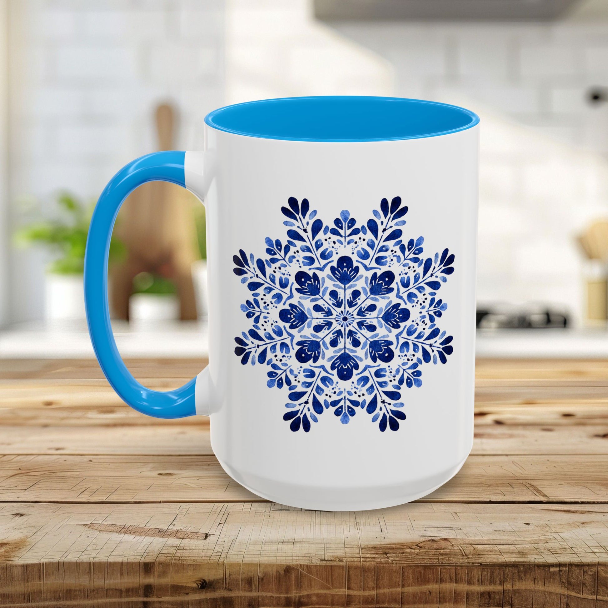 White ceramic mug with a blue floral snowflake design and a bright blue interior and C-shaped handle.
