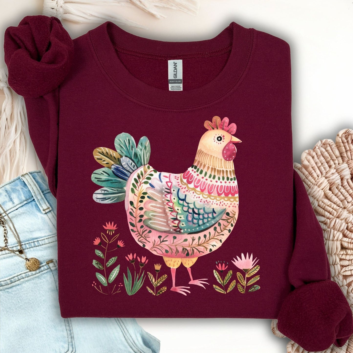 Maroon folk art chicken sweatshirt with muted pinks, teal feathers, and floral accents.