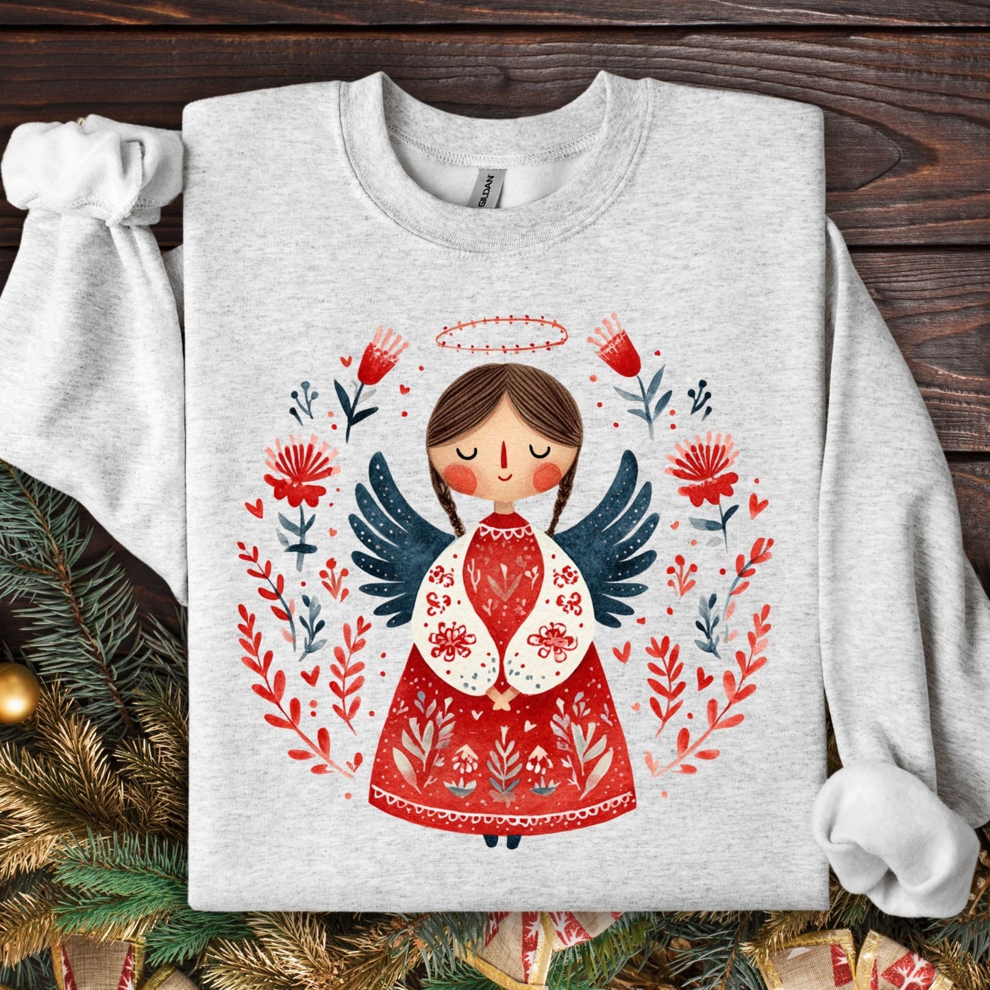 Ash Gildan sweatshirt with a folk art Christmas angel in red, green, and navy, surrounded by floral details.