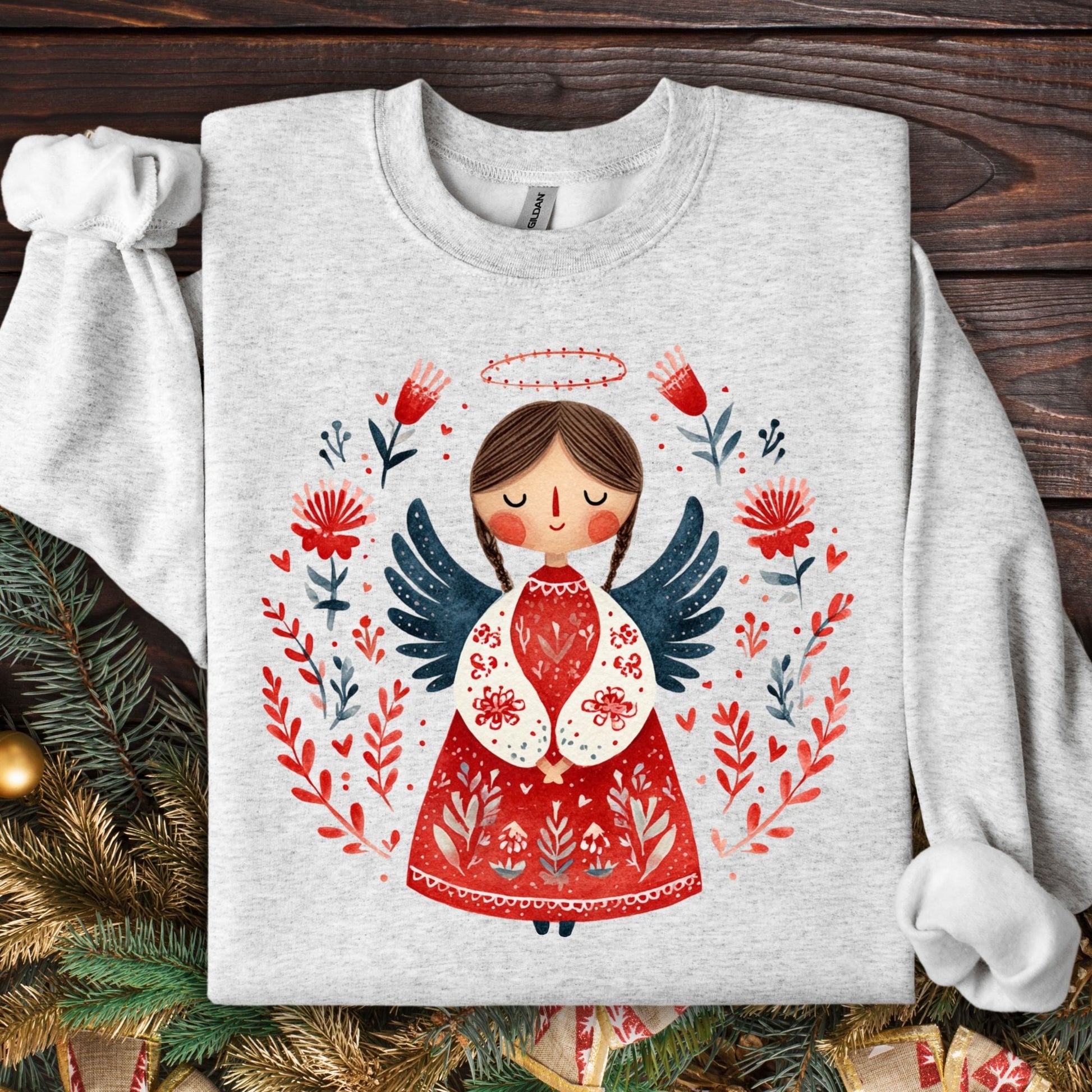 Ash Gildan sweatshirt with a folk art Christmas angel in red, green, and navy, surrounded by floral details.