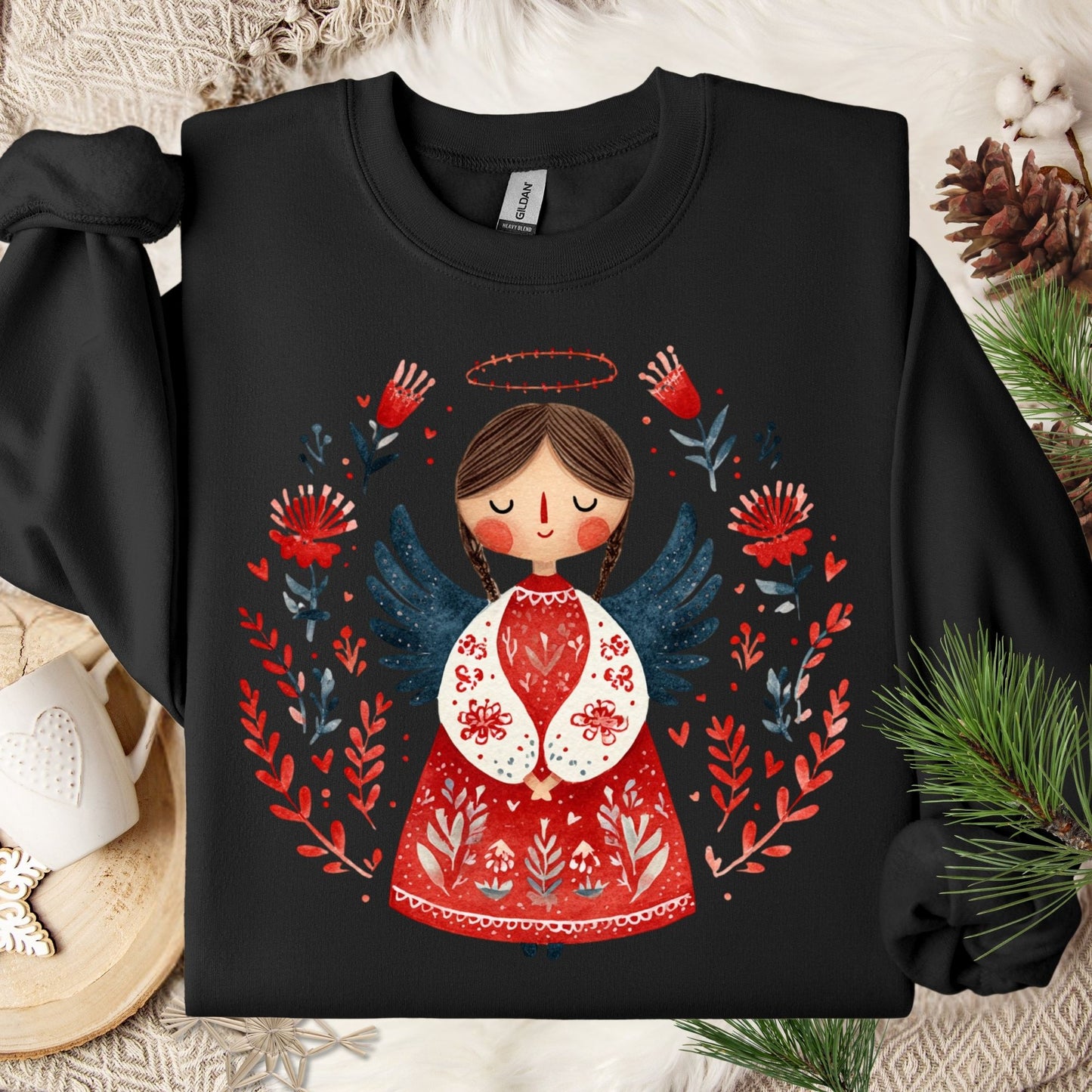 Black Gildan sweatshirt with a folk art angel in red, green, and navy, surrounded by a floral wreath.