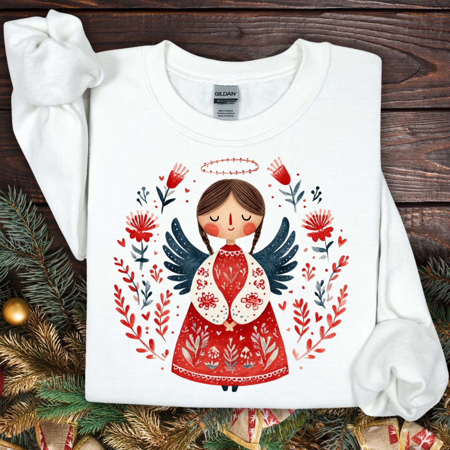 White Gildan sweatshirt with a folk art Christmas angel in red, navy, and green, surrounded by floral details.