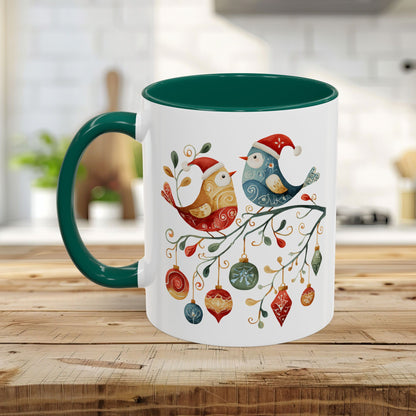 White ceramic mug with green handle and interior, featuring folk art Christmas birds and ornaments.