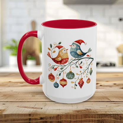 White ceramic mug with red interior and handle, featuring two folk art Christmas birds on a branch with ornaments.