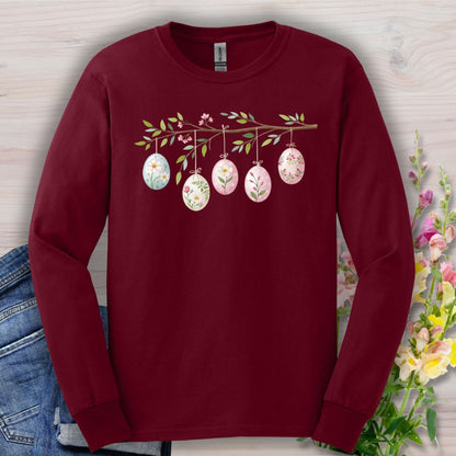 Maroon long sleeve tee with a folk art Easter egg branch design featuring floral and botanical patterns.