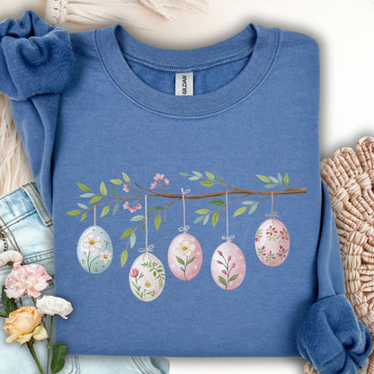 Indigo blue sweatshirt with a folk art Easter egg branch design featuring five floral watercolor eggs.