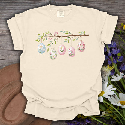 Ivory S t-shirt with a folk art Easter egg branch design featuring pastel eggs and green leaves.