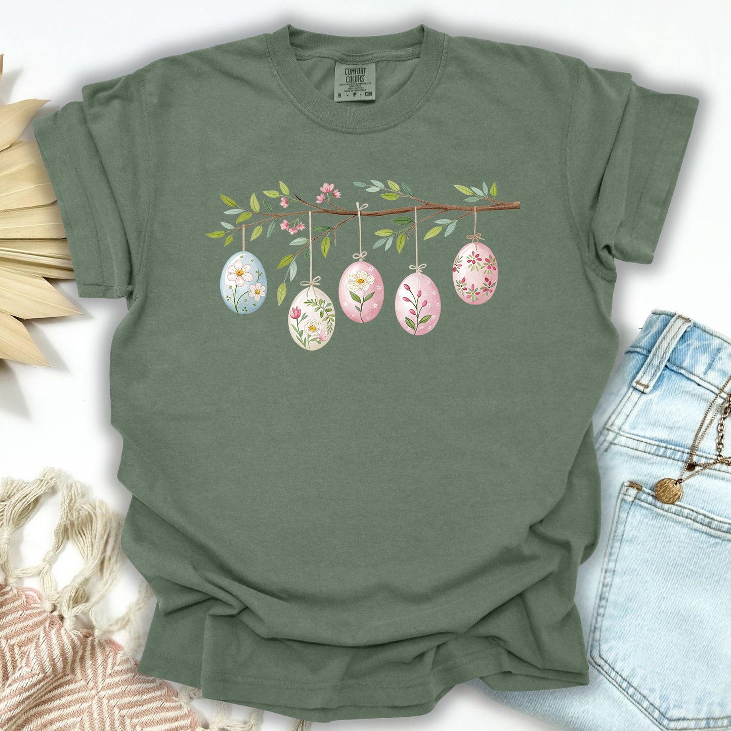 Moss green relaxed-fit t-shirt with a watercolor folk art Easter egg branch design.