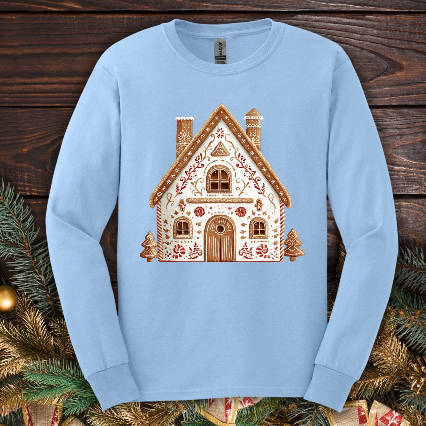 Light blue Gildan long sleeve tee with a folk art gingerbread house design in soft watercolor tones.