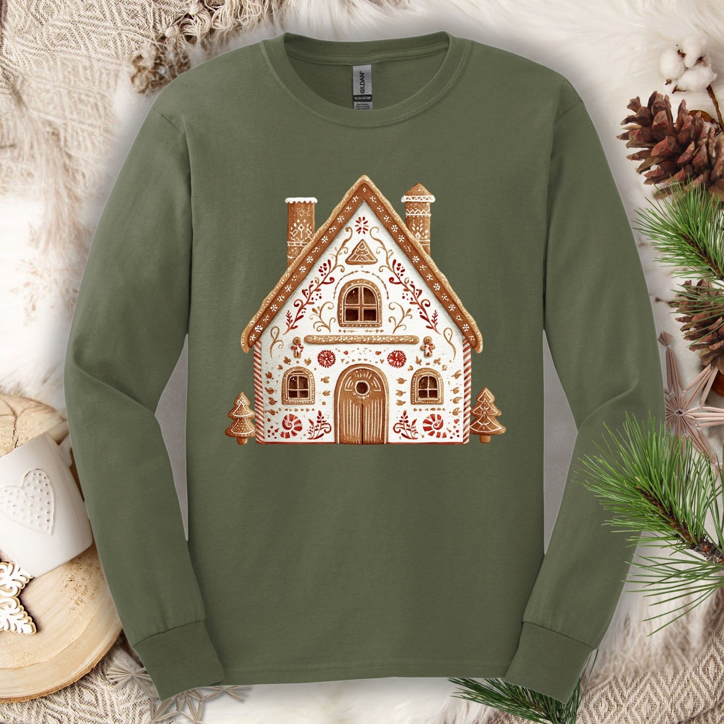 Military Green long sleeve tee with a folk art gingerbread house design in soft watercolor tones.