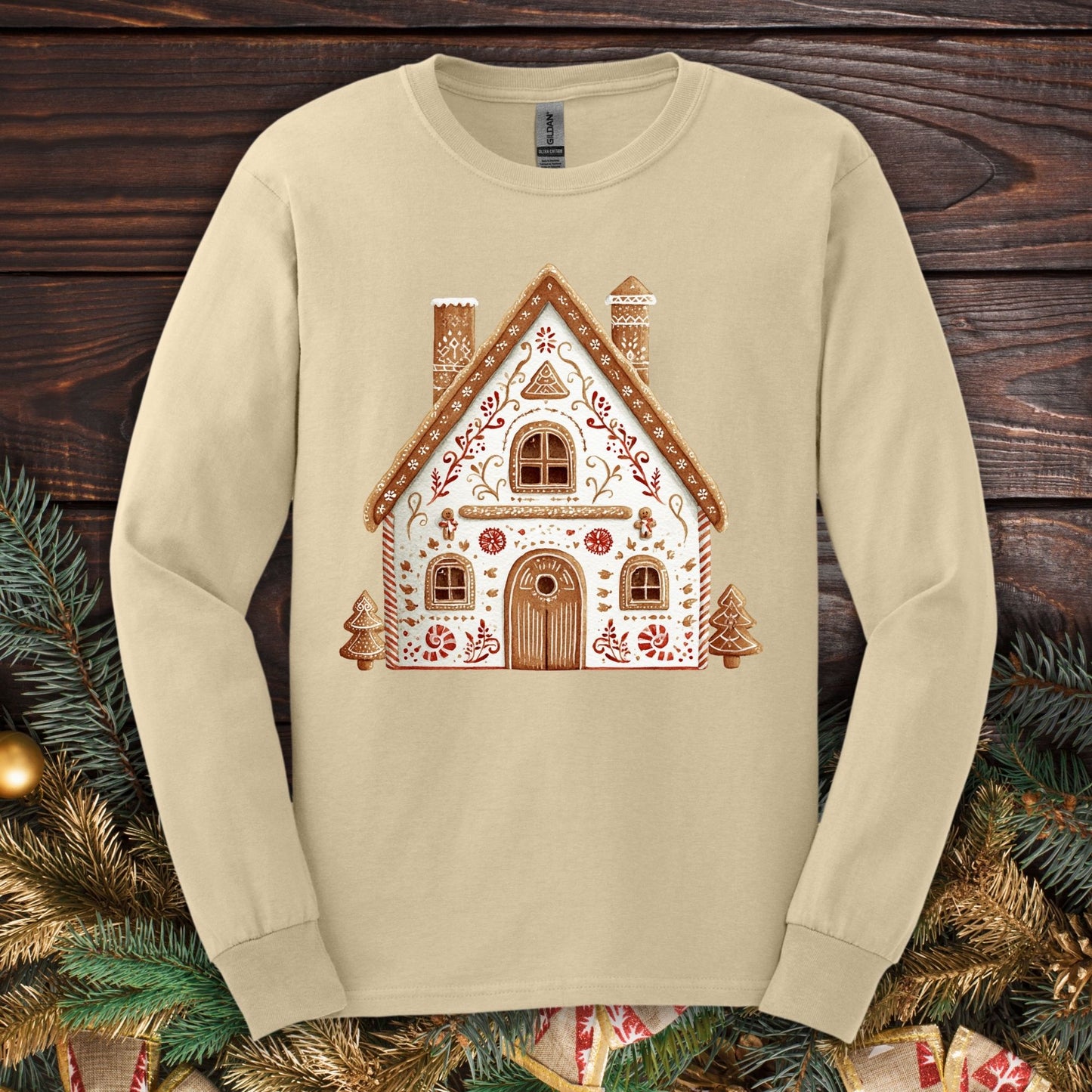 Sand Gildan long sleeve tee with a folk art gingerbread house design in watercolor tones.