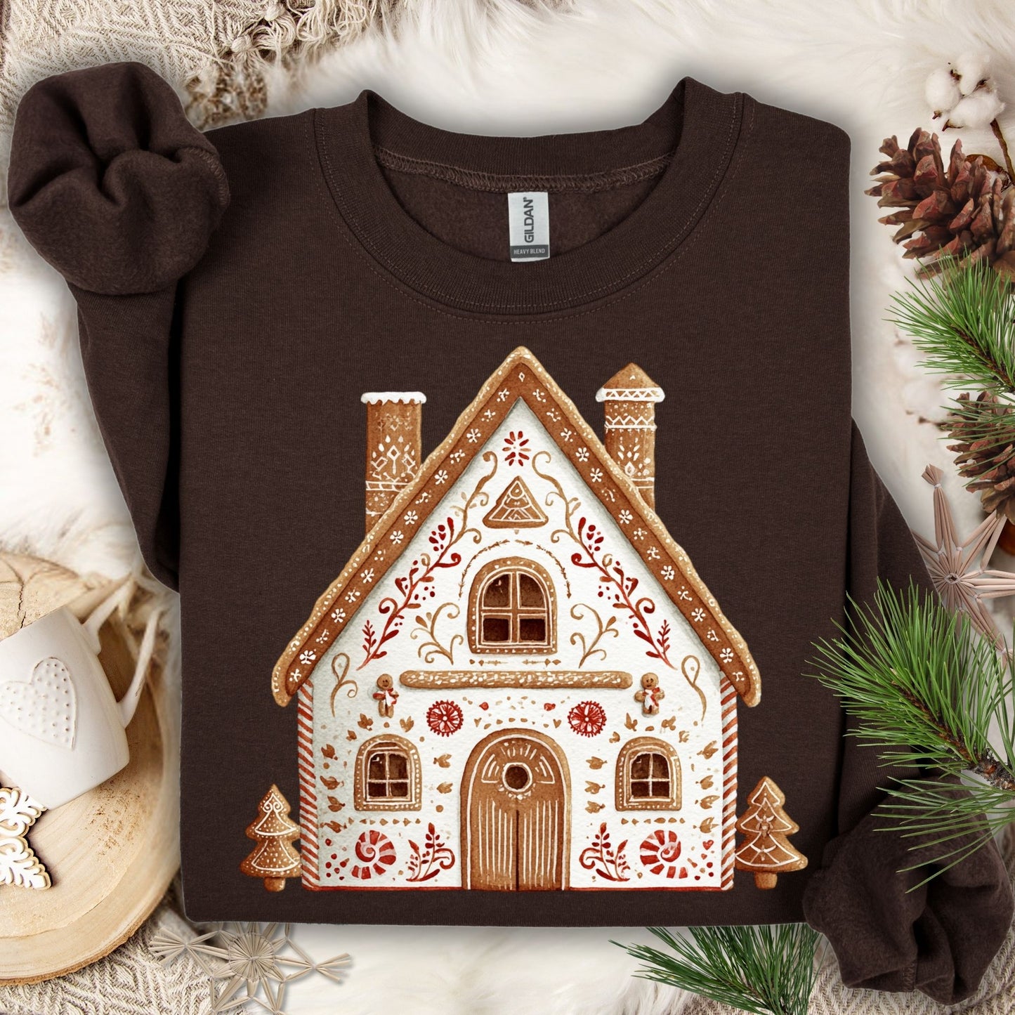 Dark Chocolate Gildan sweatshirt with a folk art gingerbread house design, surrounded by festive decor.