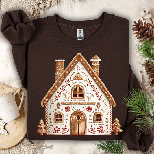 Dark Chocolate Gildan sweatshirt with a folk art gingerbread house design, surrounded by festive decor.