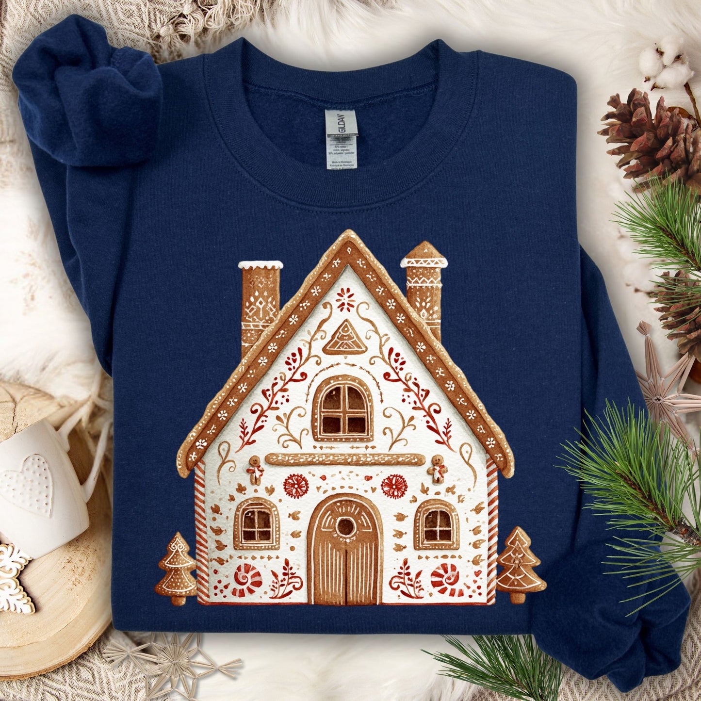 Navy Gildan sweatshirt with a folk art gingerbread house design, surrounded by festive decor.