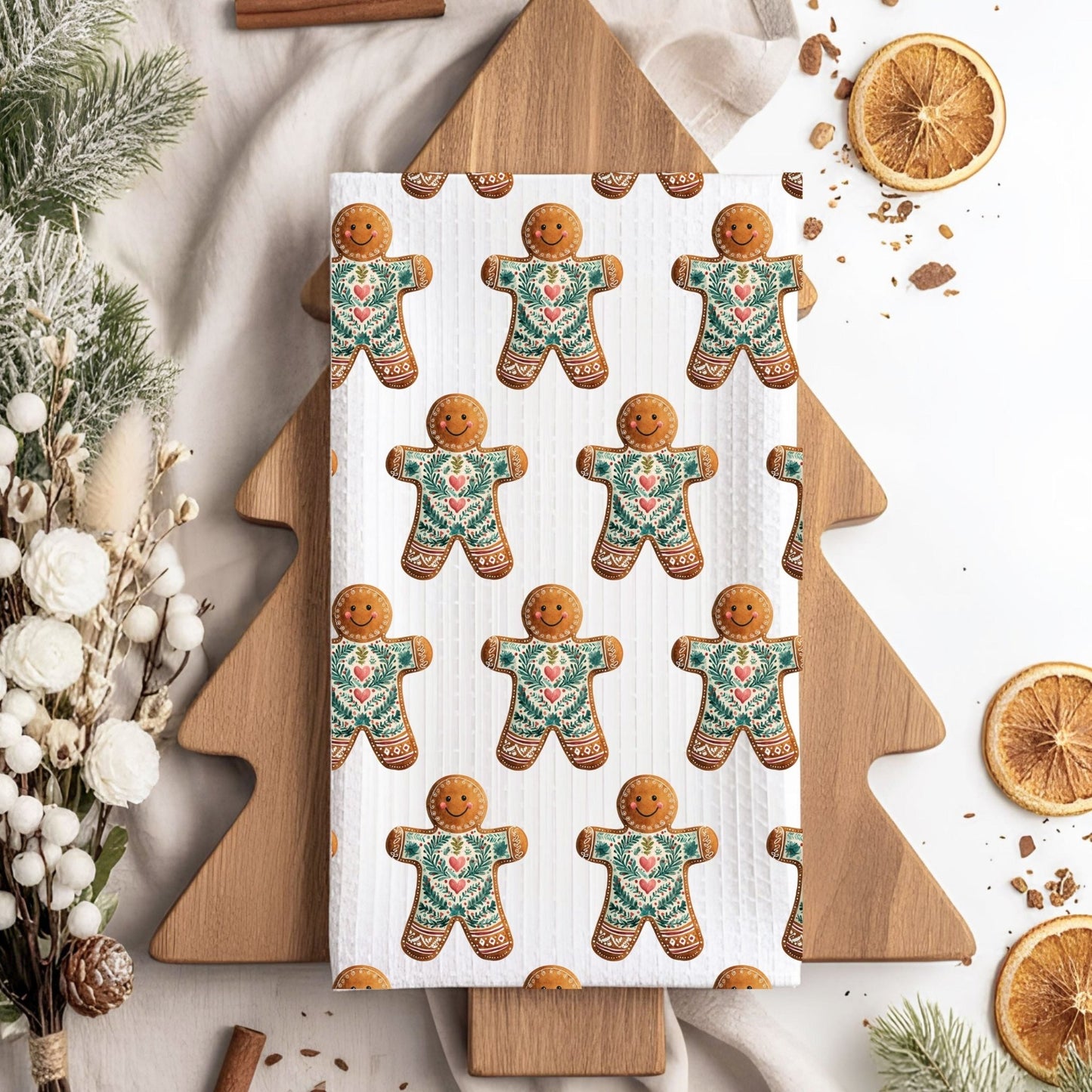 Microfiber tea towel with folk art gingerbread man pattern on a wooden tree-shaped board.
