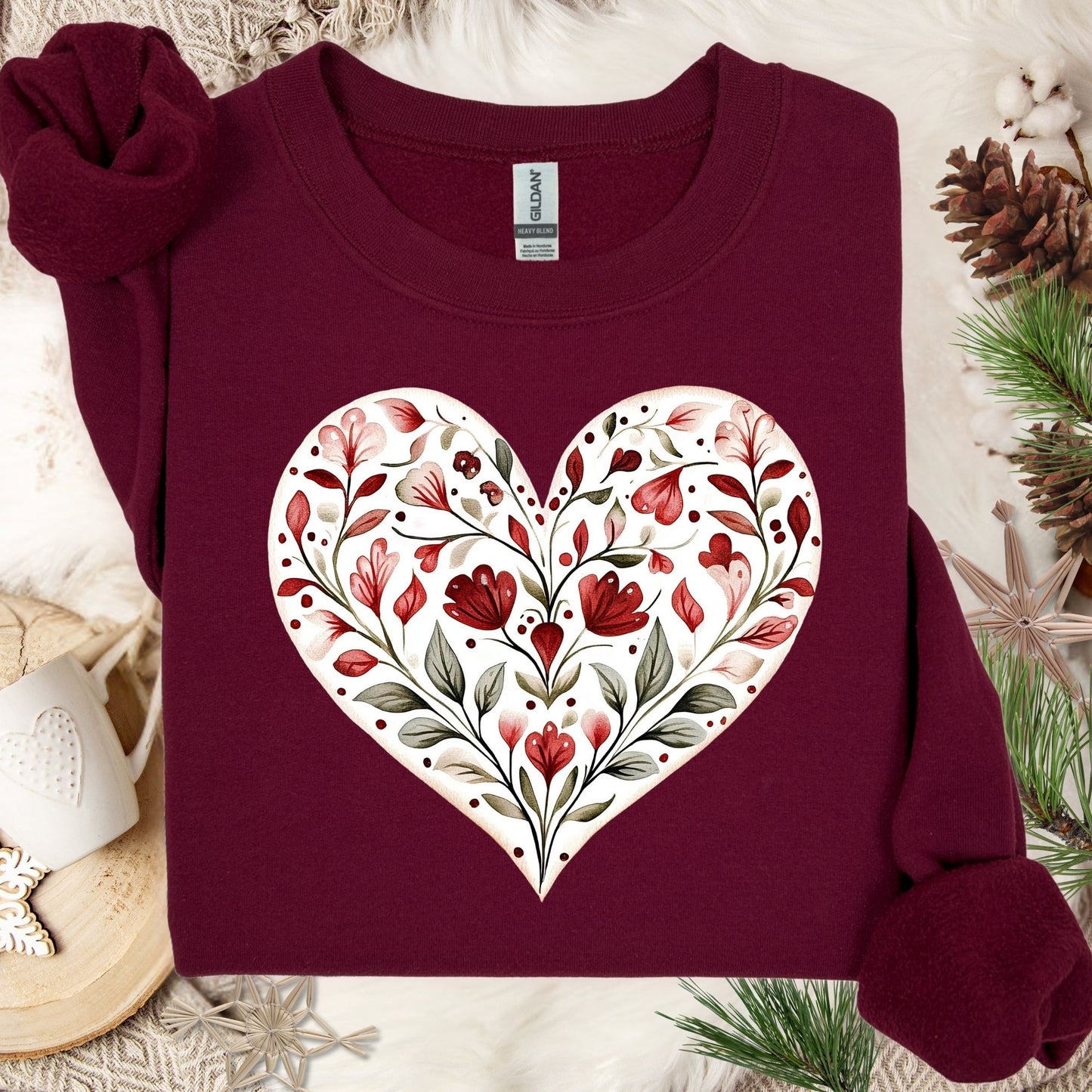 Maroon heavy blend sweatshirt with a white heart filled with red floral and green leaf folk art design.