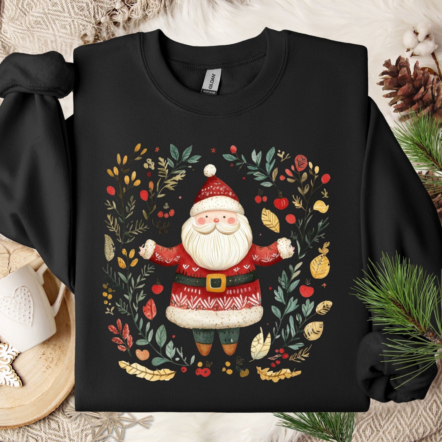 Black fleece sweatshirt with a folk art Santa in a wreath of evergreens, holly, and golden accents.