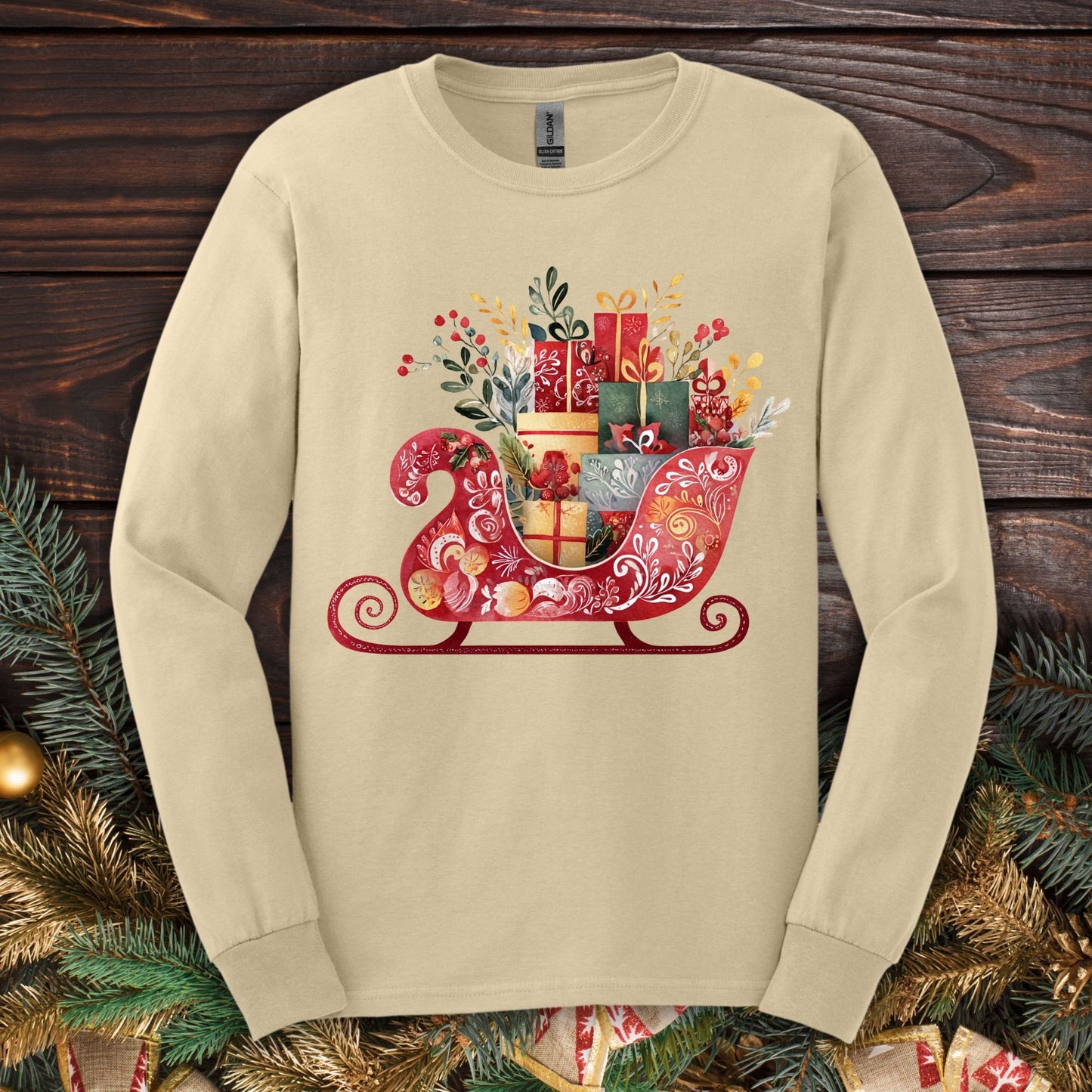 Sand Gildan long sleeve tee with a folk art Old World Christmas sleigh design, brimming with gifts.