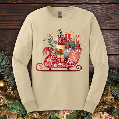 Sand Gildan long sleeve tee with a folk art Old World Christmas sleigh design, brimming with gifts.