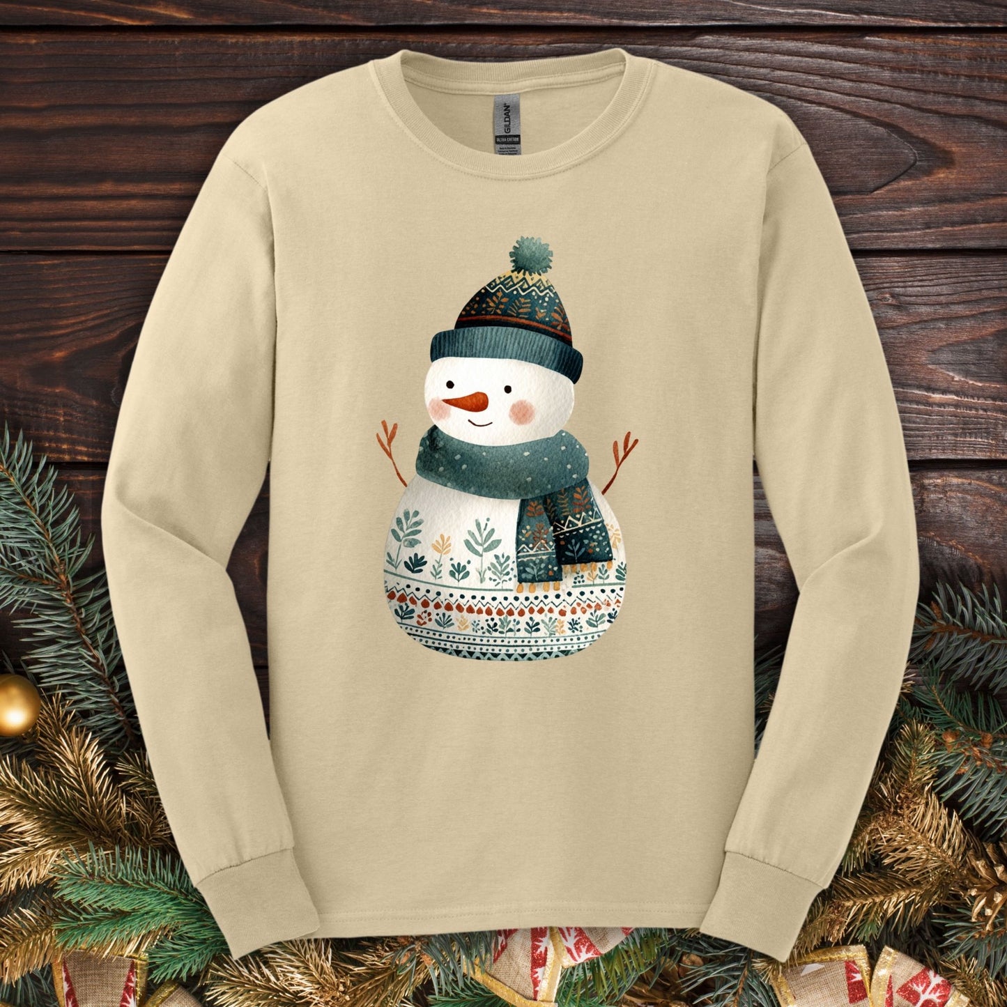 Sand Gildan long sleeve tee with a folk art snowman in a teal hat and scarf.