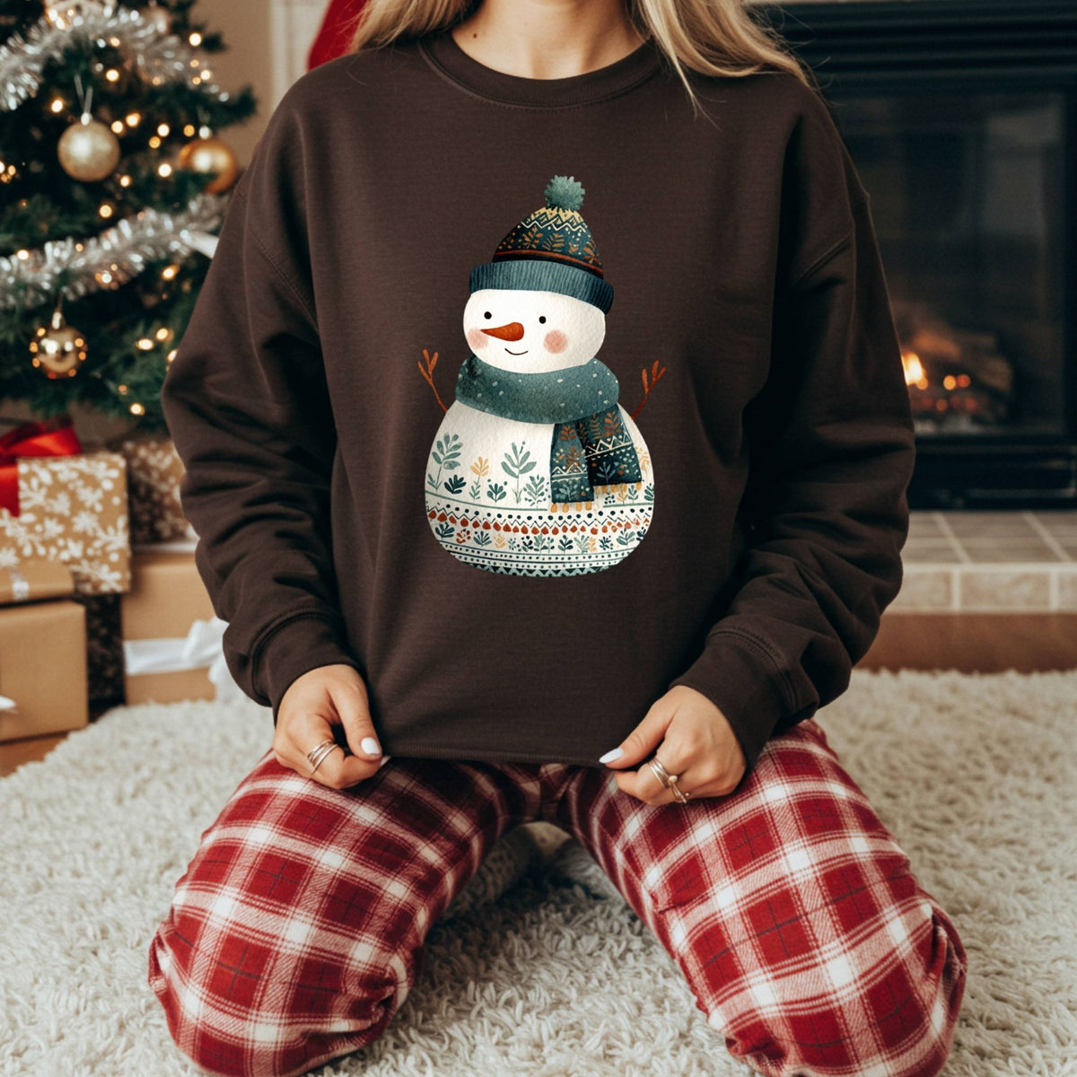 Brown Gildan crewneck sweatshirt with a folk art snowman in a teal hat and scarf, worn by a person.