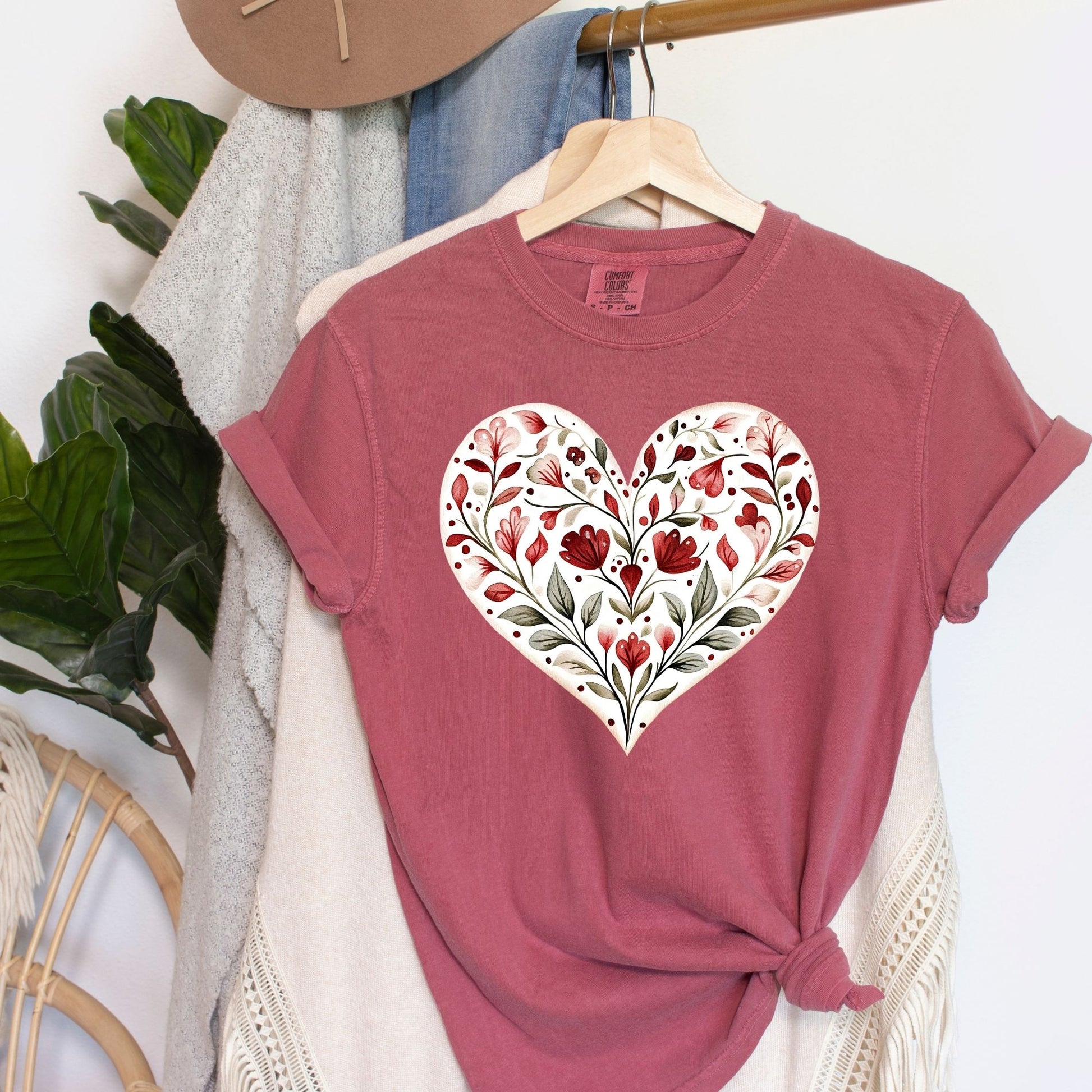 Red garment-dyed t-shirt with a white heart filled with folk-inspired red and green floral designs.