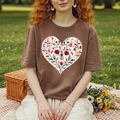 Brown relaxed-fit t-shirt with a red and green folk-inspired floral heart design, worn by a person in a park.