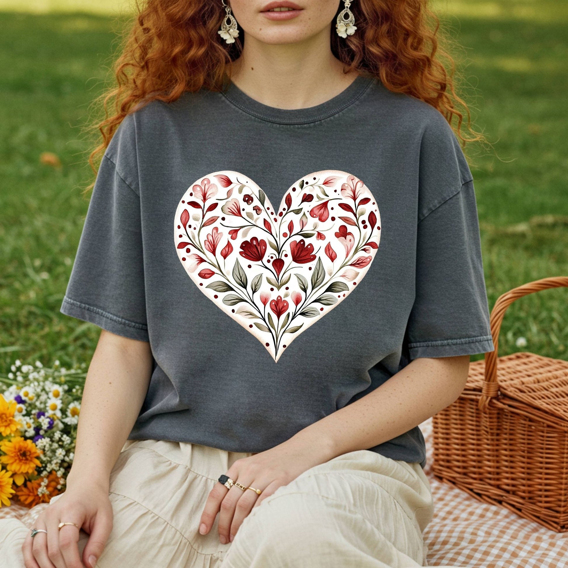 Relaxed-fit, garment-dyed charcoal t-shirt with a red floral heart design, worn by a person on a picnic blanket.