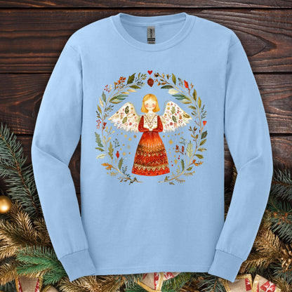 Light blue long sleeve tee with a folk art angel in a winter wreath, featuring red, green, and gold accents.